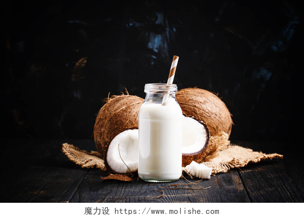 桌子上的椰子前有一瓶牛奶玻璃杯在一个玻璃瓶的椰子牛奶 